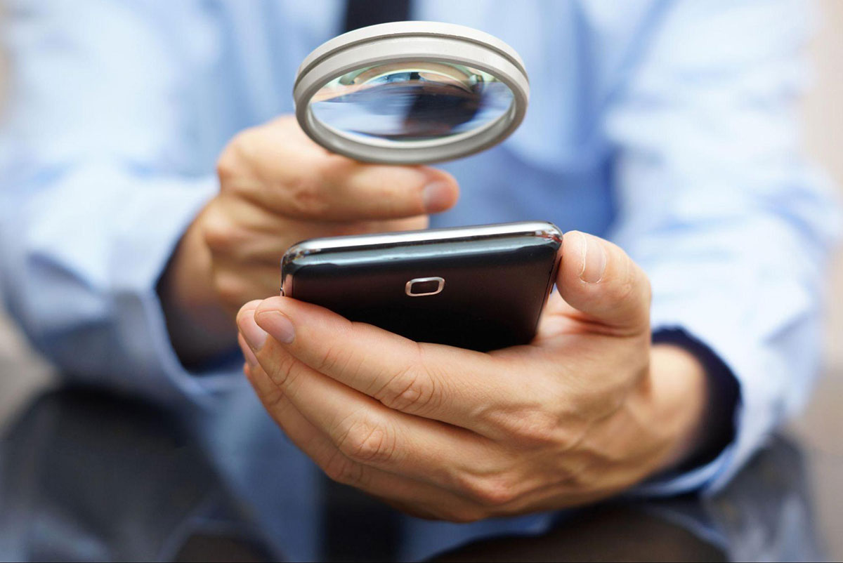 Person holding a cell phone white a magnifier glass to it