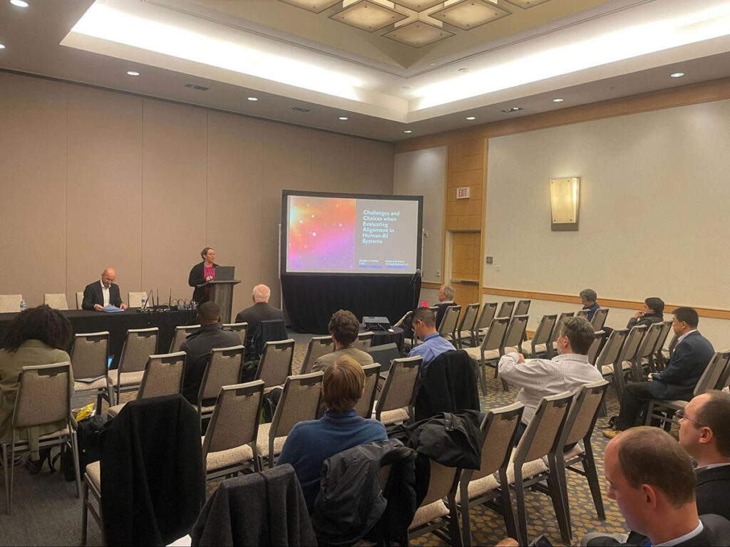 Speaker at a podium speaking to a conference room of people.
