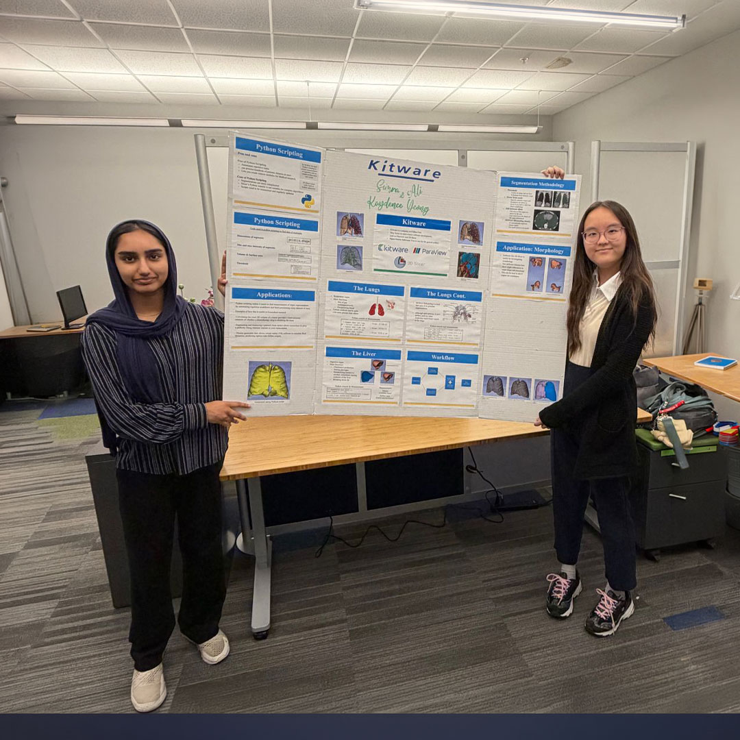 Kaydence and Simra standing in front of a presentation poster.